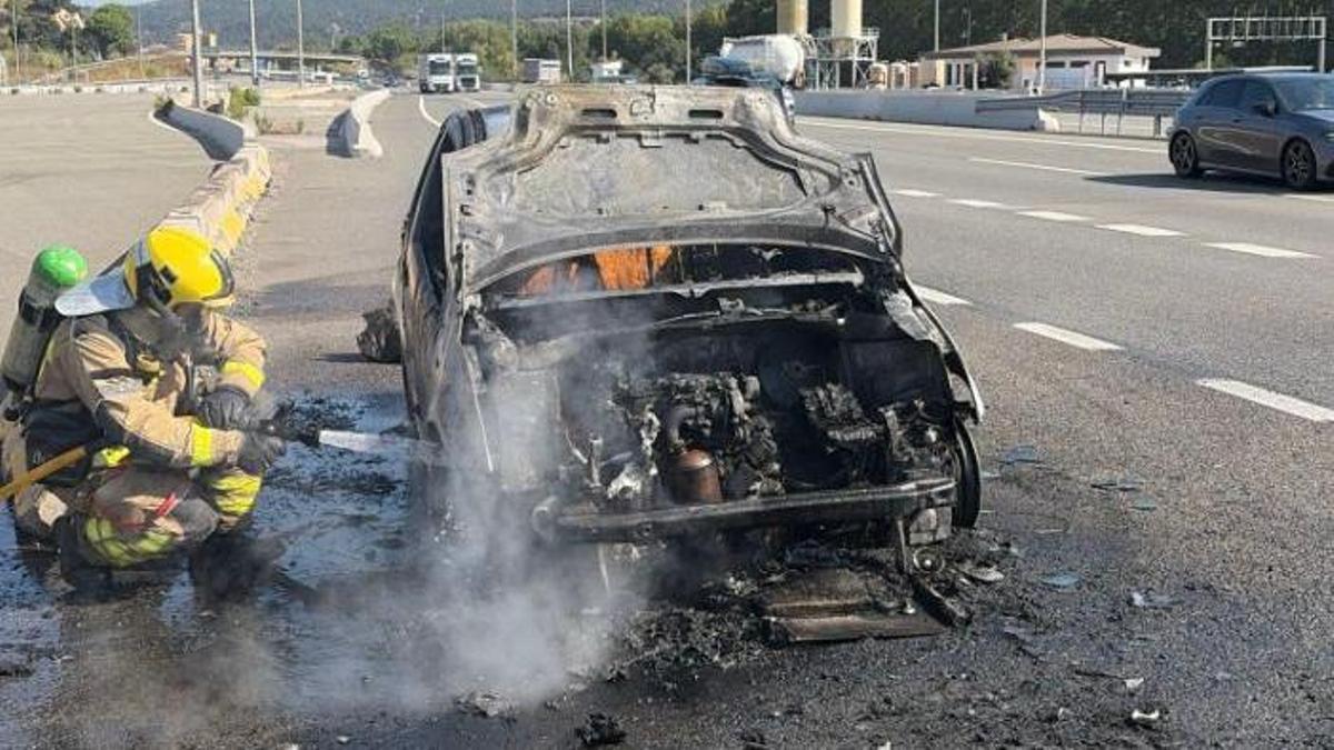 Un bomber apagant el foc del vehicle a la Jonquera.