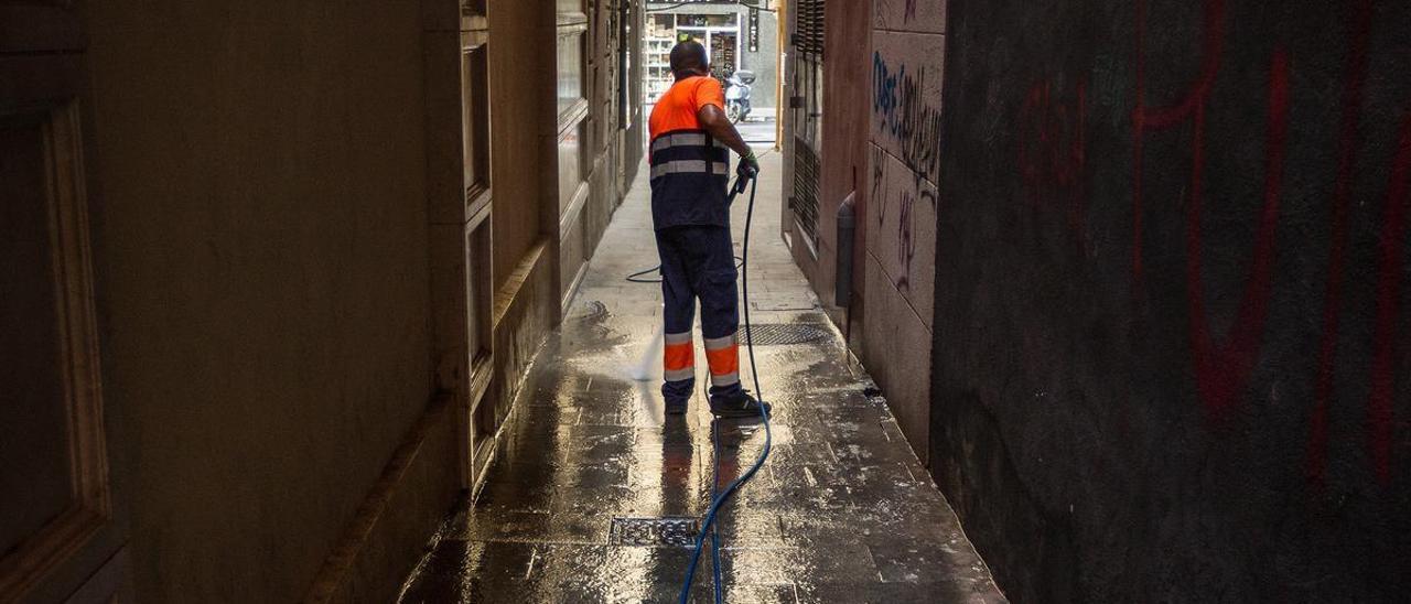 Un operario baldea una calle de Alicante, en una imagen de archivo