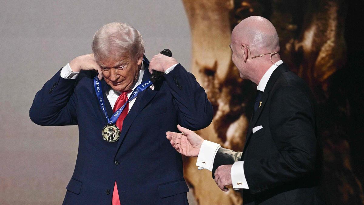 El presidente Donald Trump se coloca la medalla que representa el premio FIFA por la Paz, entregada por el presidente de la FIFA, Gianni Infantino