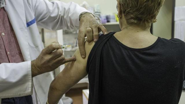 Un profesional sanitario inocula a una mujer la vacuna contra la gripe . | L.O.Z