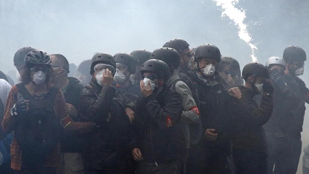 Manifestantes se protegen de los gases lacrimógenos.