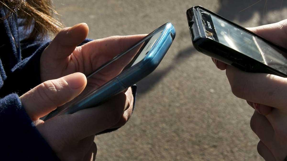 Dos jóvenes consultan sus teléfonos móviles. FERRAN NADEU