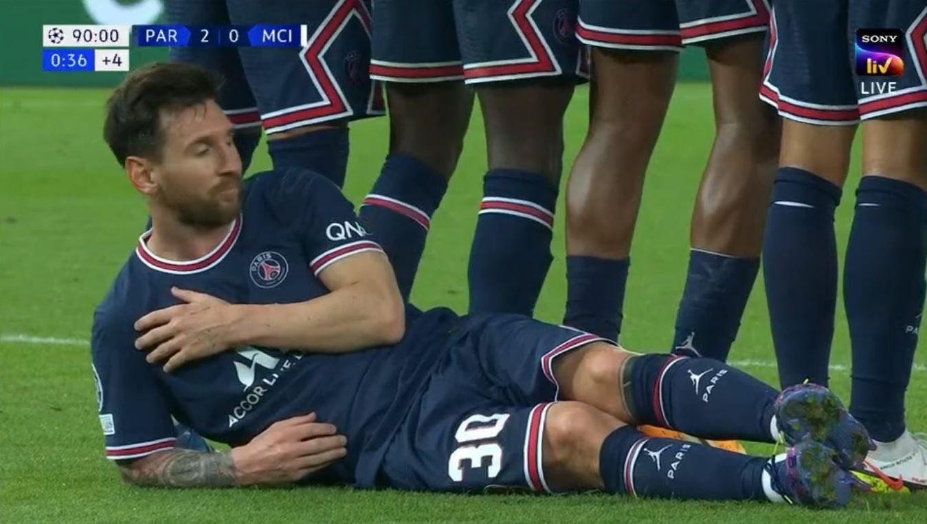 Leo Messi se coloca en el suelo, por debajo de la barrera, en el tiempo de prolongación del PSG - Manchester City