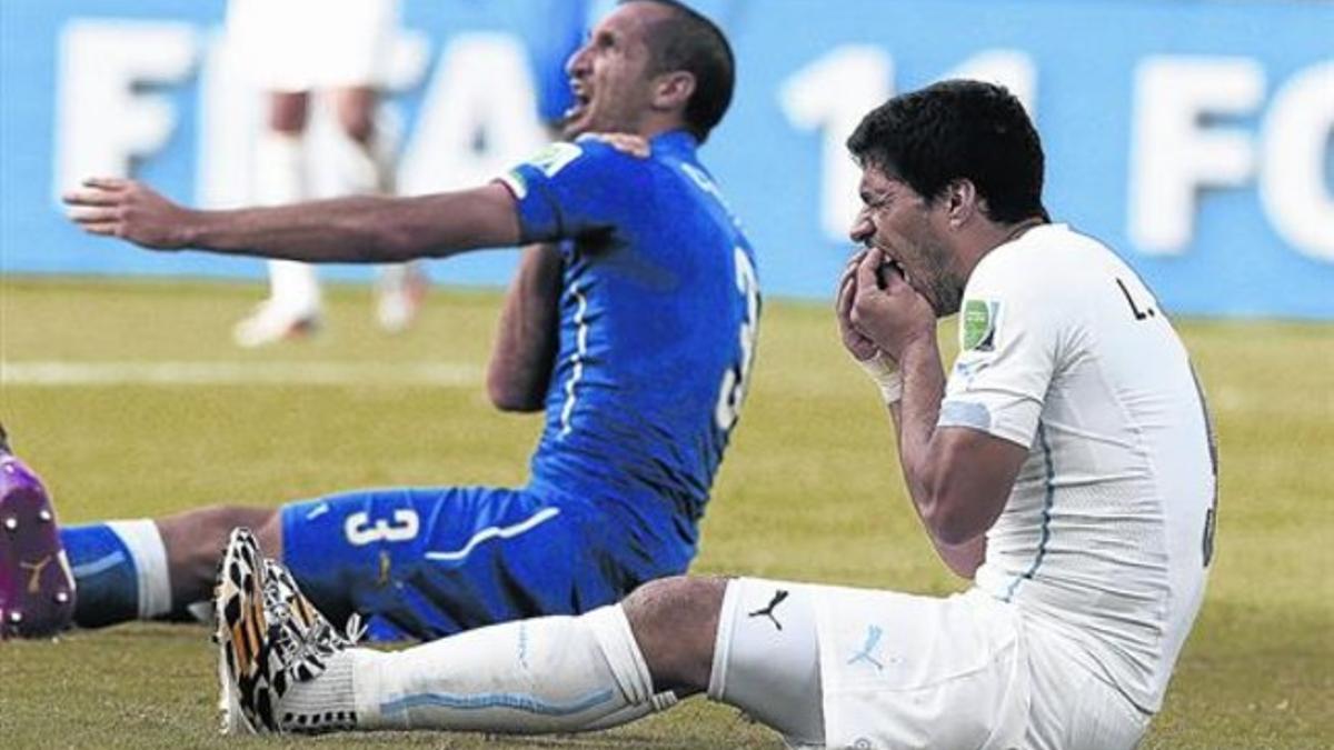 Chiellini se queja al árbitro del mordisco de Suárez, que se duele de los dientes, durante el Italia-Uruguay del Mundial de Brasil.