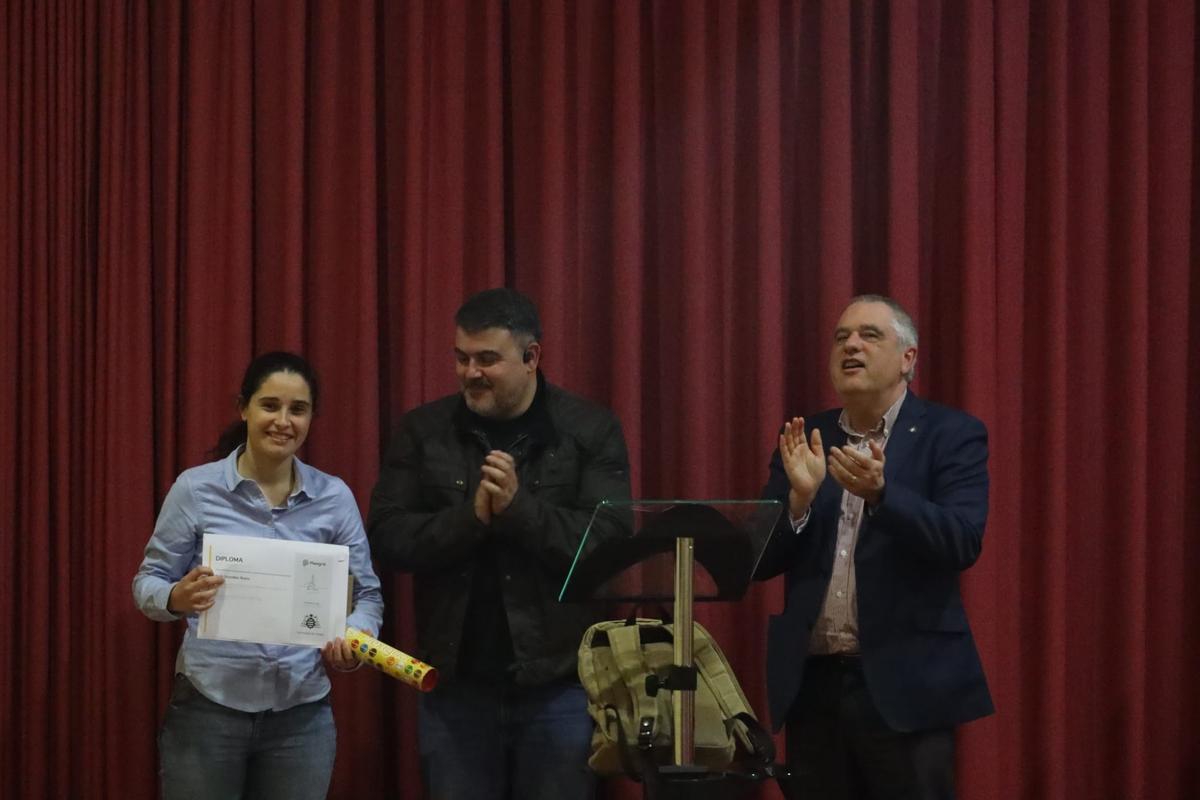 María González Busto recoge el premio de manos del catedrático Pablo Arboleya, en presencia del director del departamento, Hilario López.