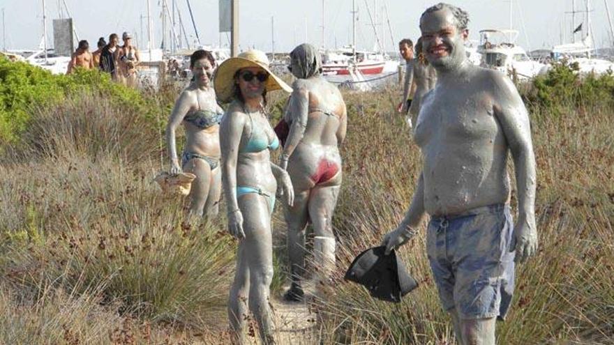 Unos bañistas a punto de quitarse el barro en la playa de s´Alga tras sumergirse en el lodo de s´Espalmador.