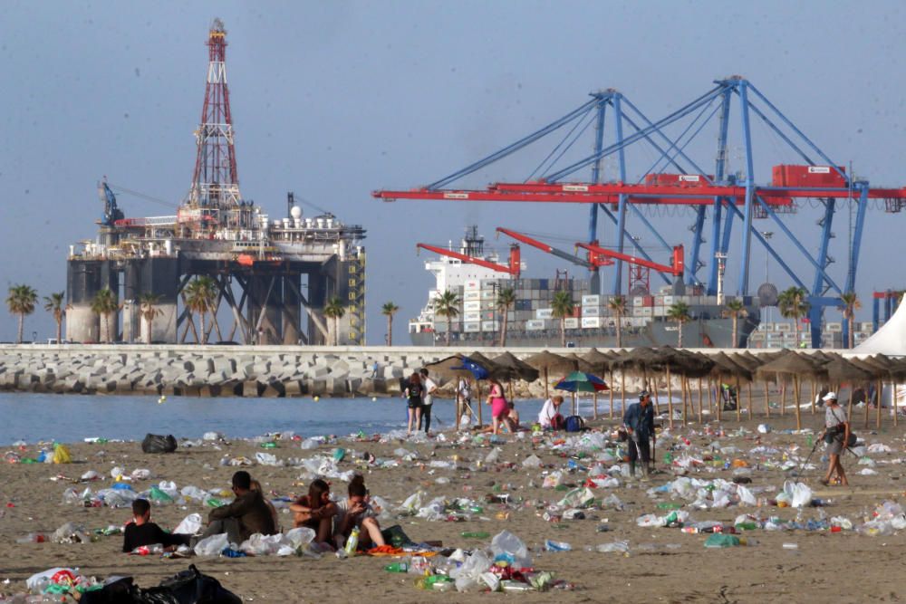 Los operarios de los servicios de limpieza trabajan para dejar la playa en óptimas condiciones tras una larga noche de fiesta en la arena