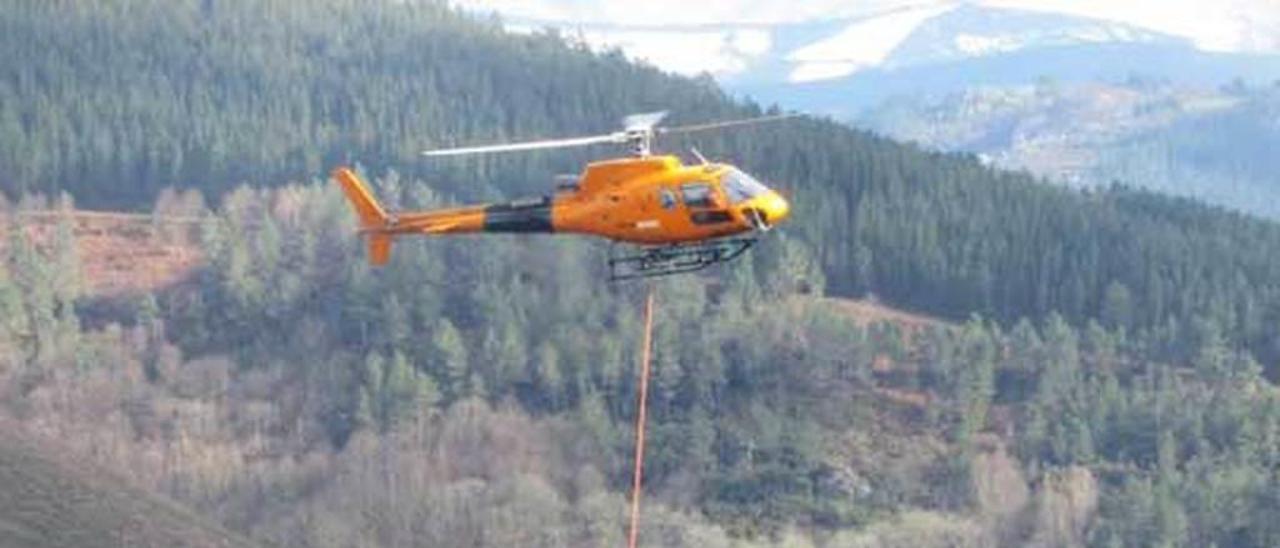 Dos operarios colocan cable conductor en una torre de la línea Boimente-Pesoz con la ayuda de un helicóptero.