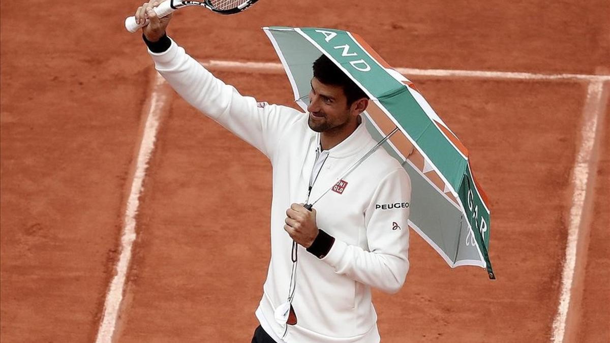 Djokovic bromea con un paraguas en la central de Roland Garros en otra jornada suspendida por la lluvia.