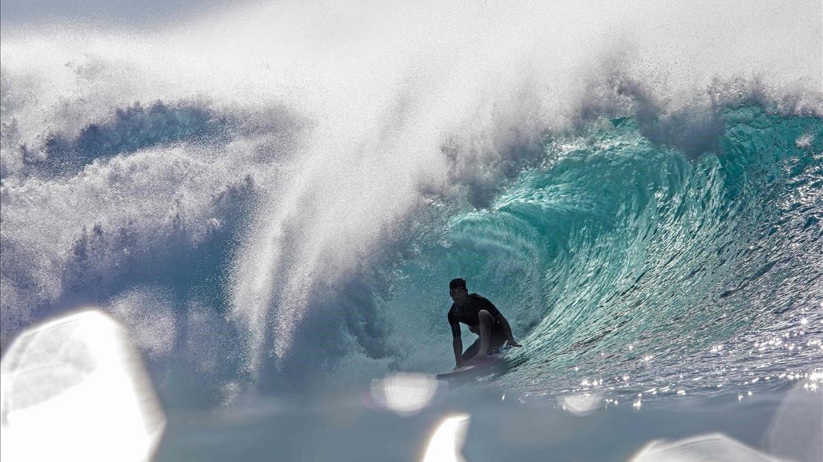 Un surfer se desliza por una ola entrenándose para el Pipeline Masters en la costa norte de Oahu, Hawaii.