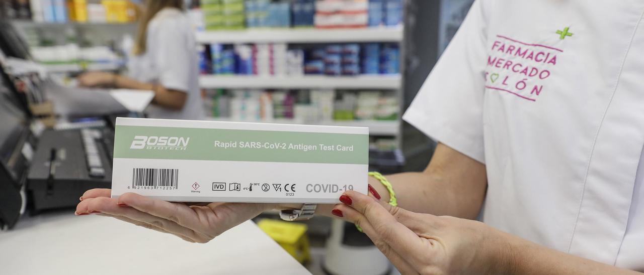 Una farmacéutica muestra una caja de test de antígenos