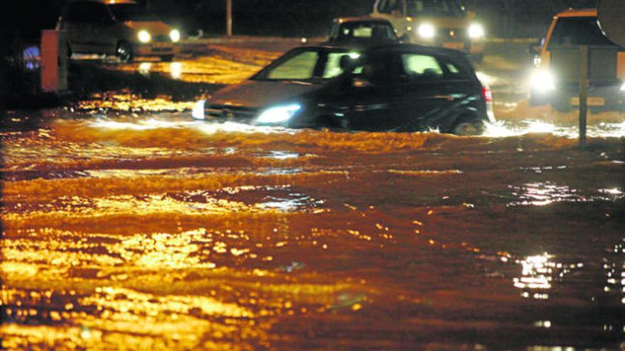 El agua llegaba a la altura de los faros de este coche anoche en la rotonda de entrada al puerto de Vila.