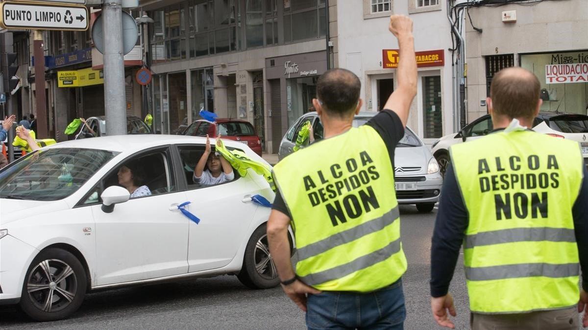 Dos trabajadores de Alcoa saludan a otros que llegan a Lugo durante la marcha de coches en caravana convocada el 28 de junio del 2020