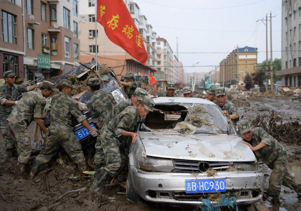 Rescue workers drag damaged cars out of debris ...