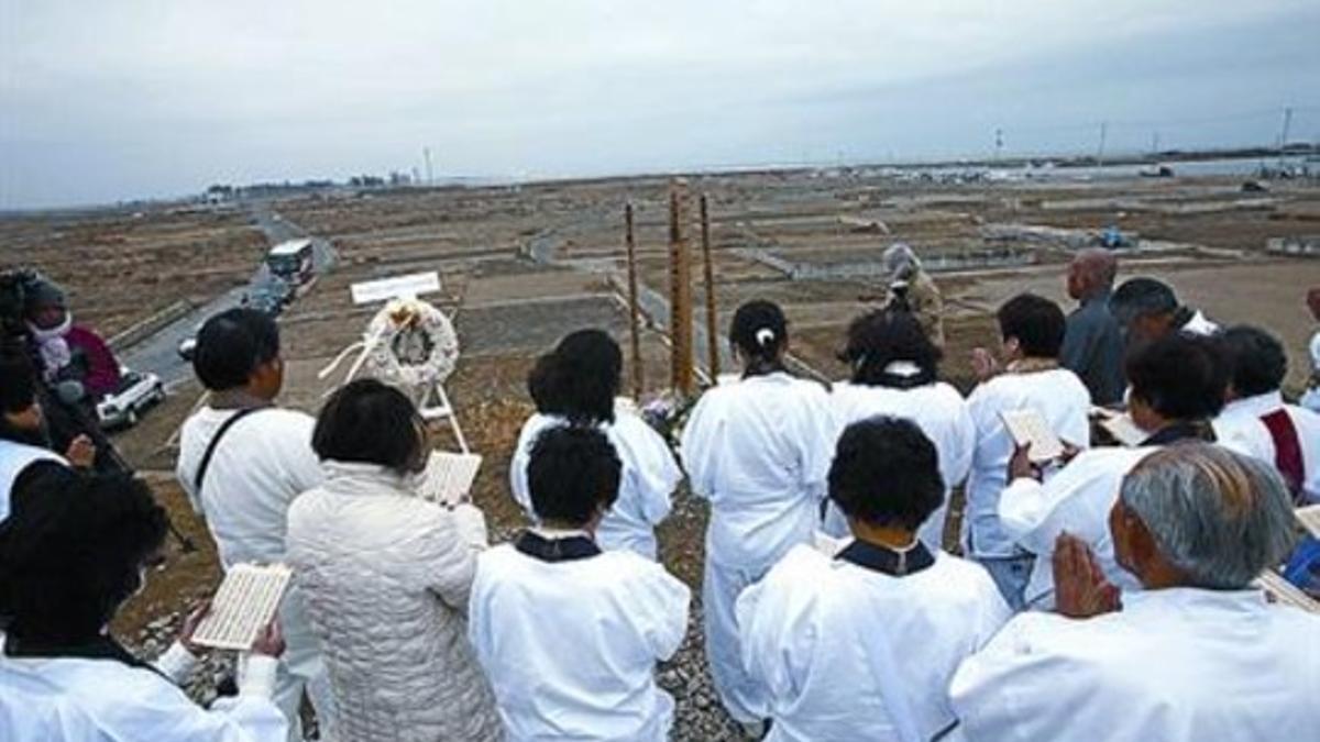 Un grupo de japoneses reza por las víctimas del tsunami en Natori, ayer.