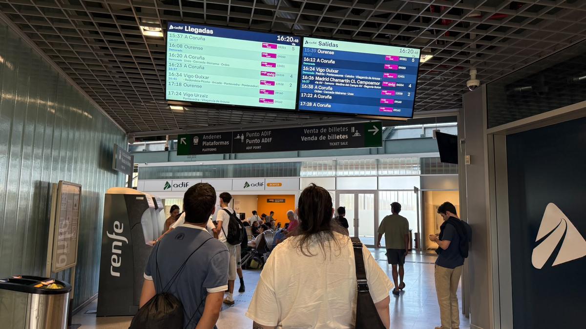 Pareja mirando los retrasos en la pantalla de información en Santiago de Compostela