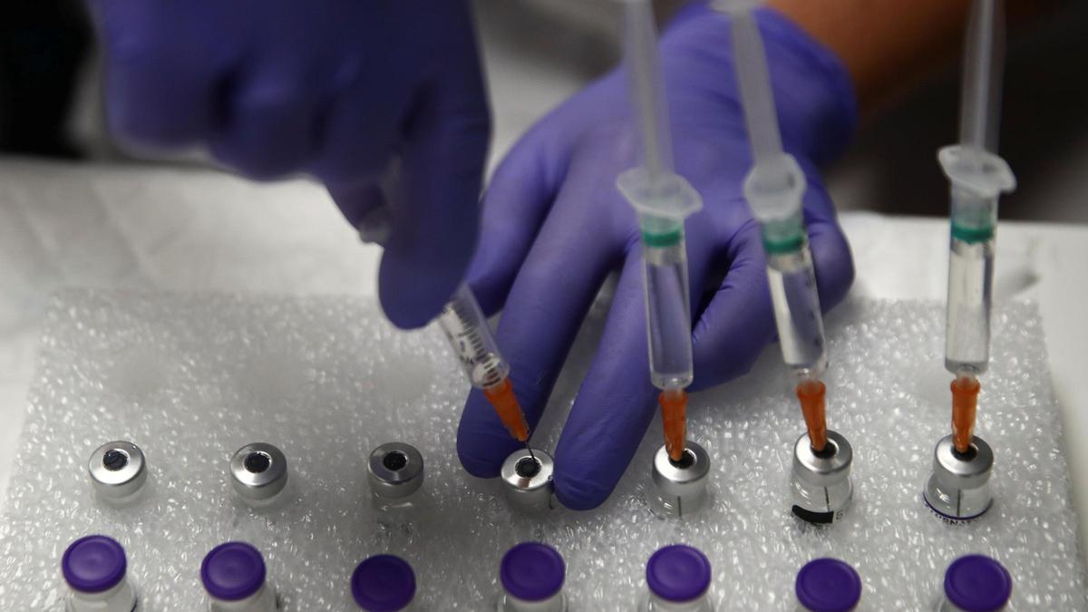 A medical worker use saline solution to prepare doses of the &quot;Comirnaty&quot; Pfizer-BioNTech COVID-19 vaccine in Madrid