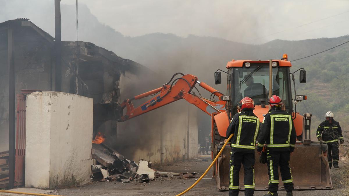 La retroexcavadora del Ayuntamiento, controlada por un trabajador municipal, ha ayudado a derribar un muro para abordar la extinción.