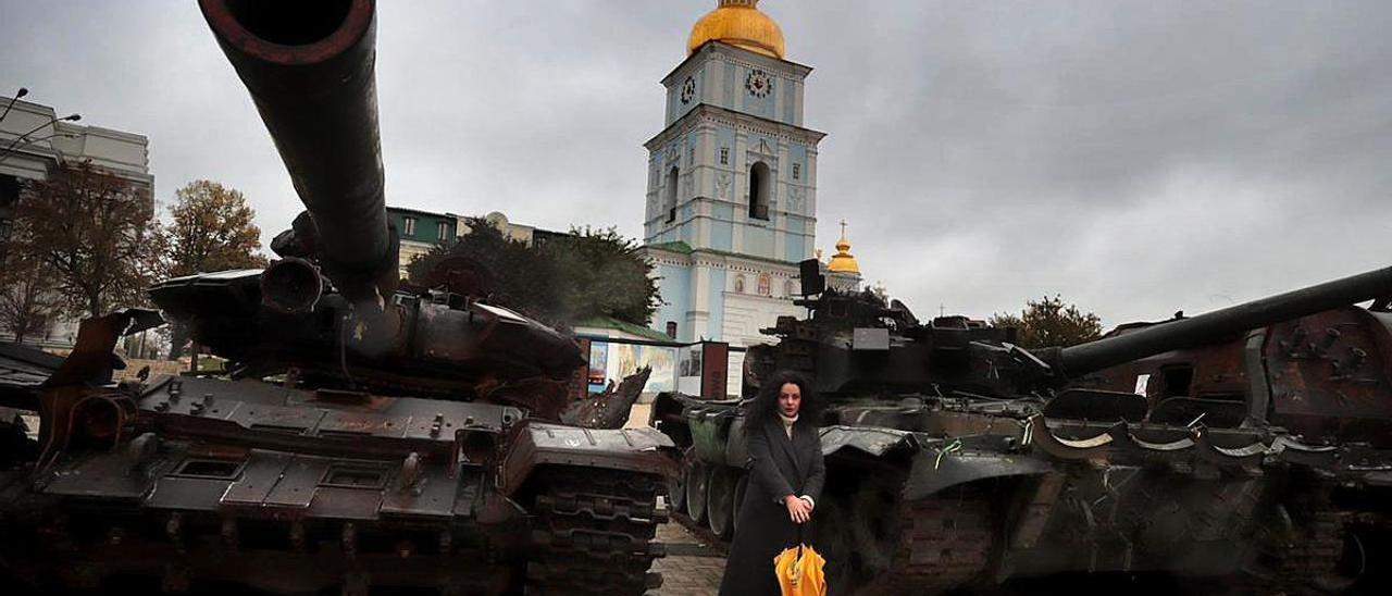 Olga Oibrova se fotografía frente a blindados y tanques rusos exhibidos frente a una iglesia de Kiev.