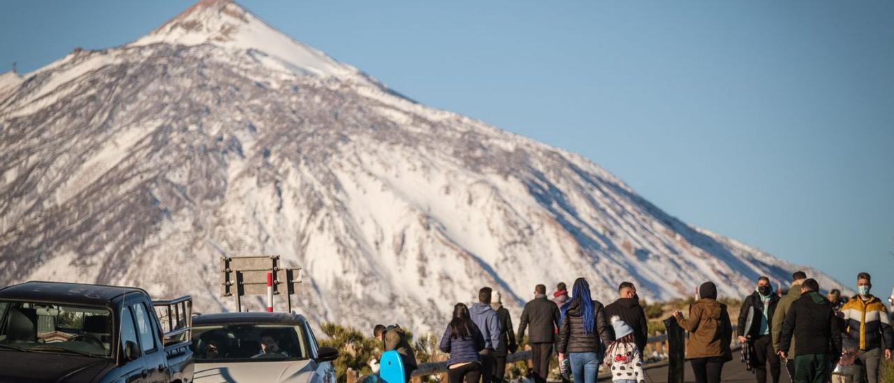 Personas y vehículos en el interior del Parque Nacional del Teide en un día de nevada. | | ANDRÉS GUTIÉRREZ
