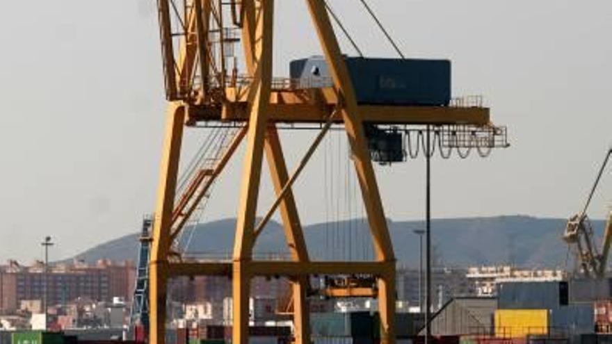 Un velero pasa junto a un muelle de contenedores.