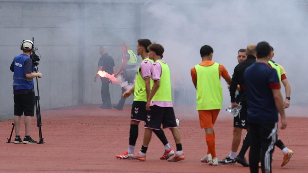 La seguridad privada del estadio recoge una de las bengalas lanzadas al interior del campo.