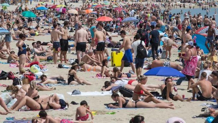 La playa del Postiguet llena de turistas y residentes que aprovechan las altas temperaturas del domingo, ya comenzada la Semana Santa.