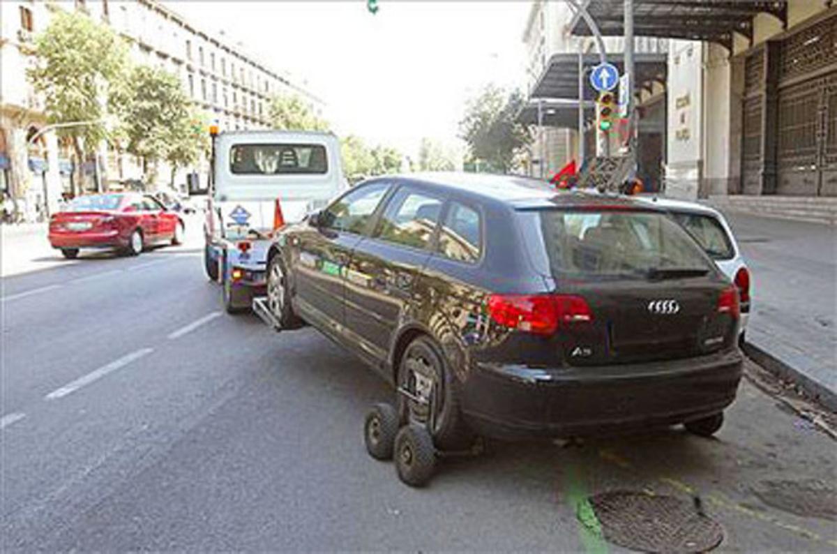 Una grua retira un cotxe mal aparcat a Barcelona (la matrícula ha estat tapada). Una grua retira un cotxe mal aparcat a Barcelona (la matrícula ha estat tapada).