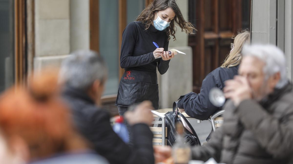 Una camarera atiende a varios clientes en una terraza.