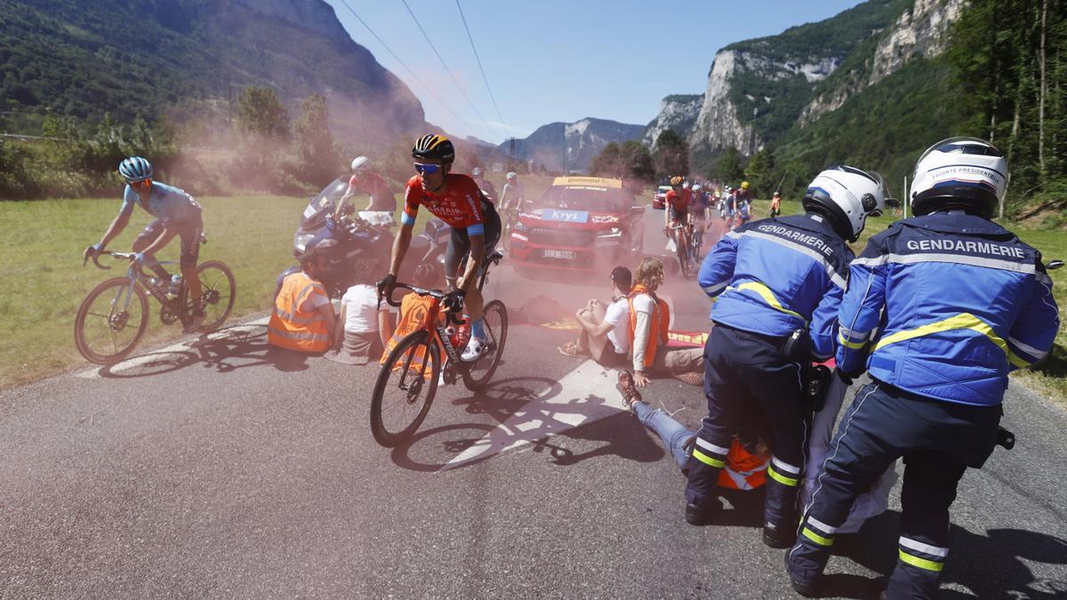 Luis León Sánchez  pasa cerca de los manifestantes sentados en la carretera protestando, mientras la policía intenta sacarlos, durante la décima etapa del Tour de Francia 2022 desde Morzine a Megeve.