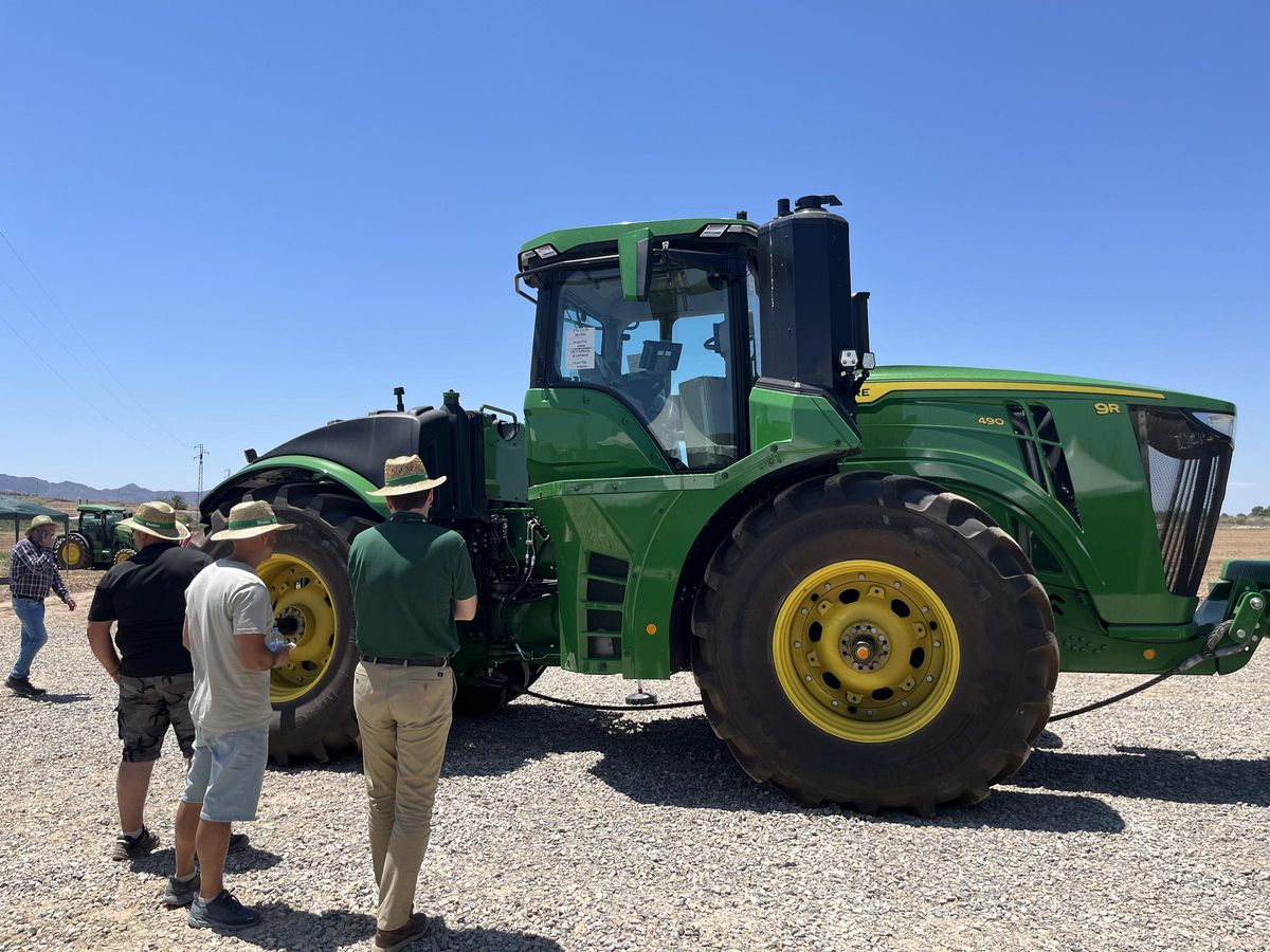Clientes y comercial con John Deere 9R en exposición