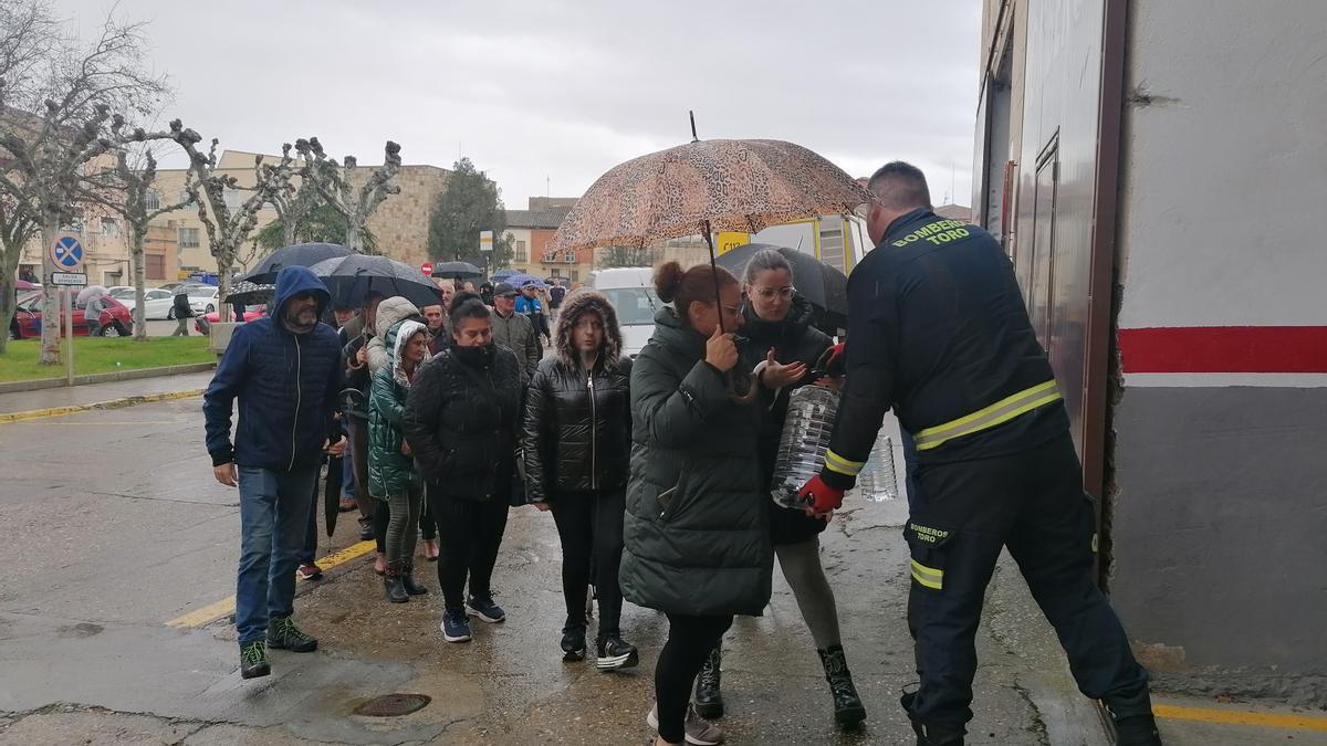 Un bombero entrega una garrafa de agua a unas vecinas