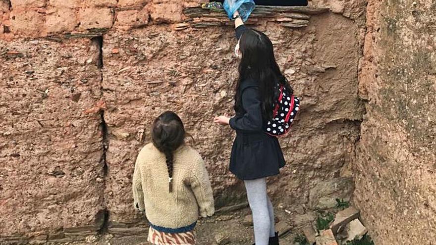 Dos niñas recogen uno de los guijarros con una bolsa de plástico. | Cedida