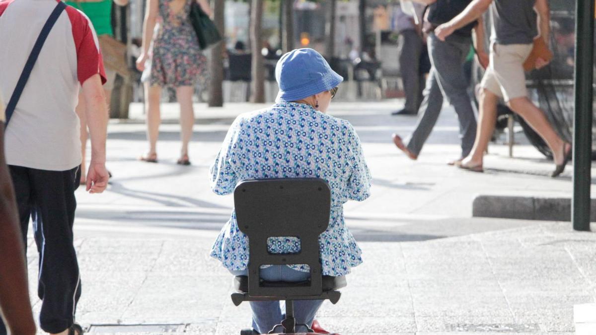 Una mujer se mueve con una silla de ruedas eléctrica por el paseo Independencia de Zaragoza. | CHUS MARCHADOR