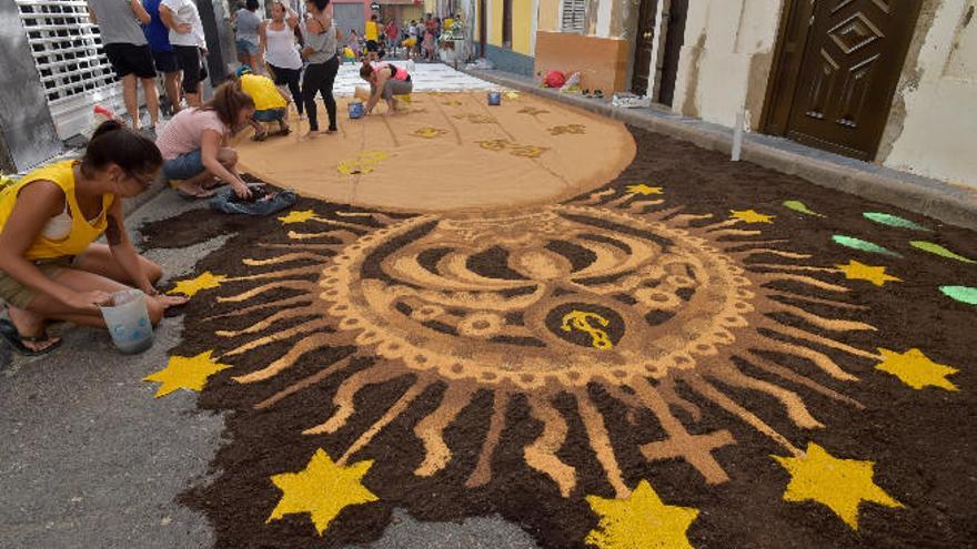 Los vecinos de la calle Romeral, ayer, mientras se afanan en la creación de la alfombra.