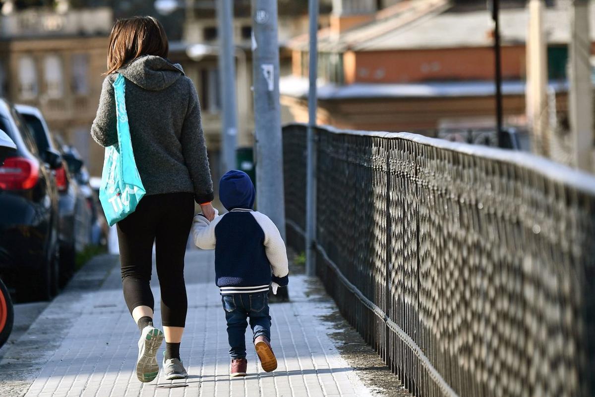 Genoa (Italy), 30/03/2020.- A yhoung woman and a toddler walk along a street as all playgrounds for children remain closed and empty due to the rules against the spread of the SARS-CoV-2 coronavirus which causes the COVID-19 disease, in Genova, Italy, 30 March 2020. Countries around the world are increasing their efforts nd measures to stem the widespread of the disease. (Italia) EFE/EPA/LUCA ZENNARO