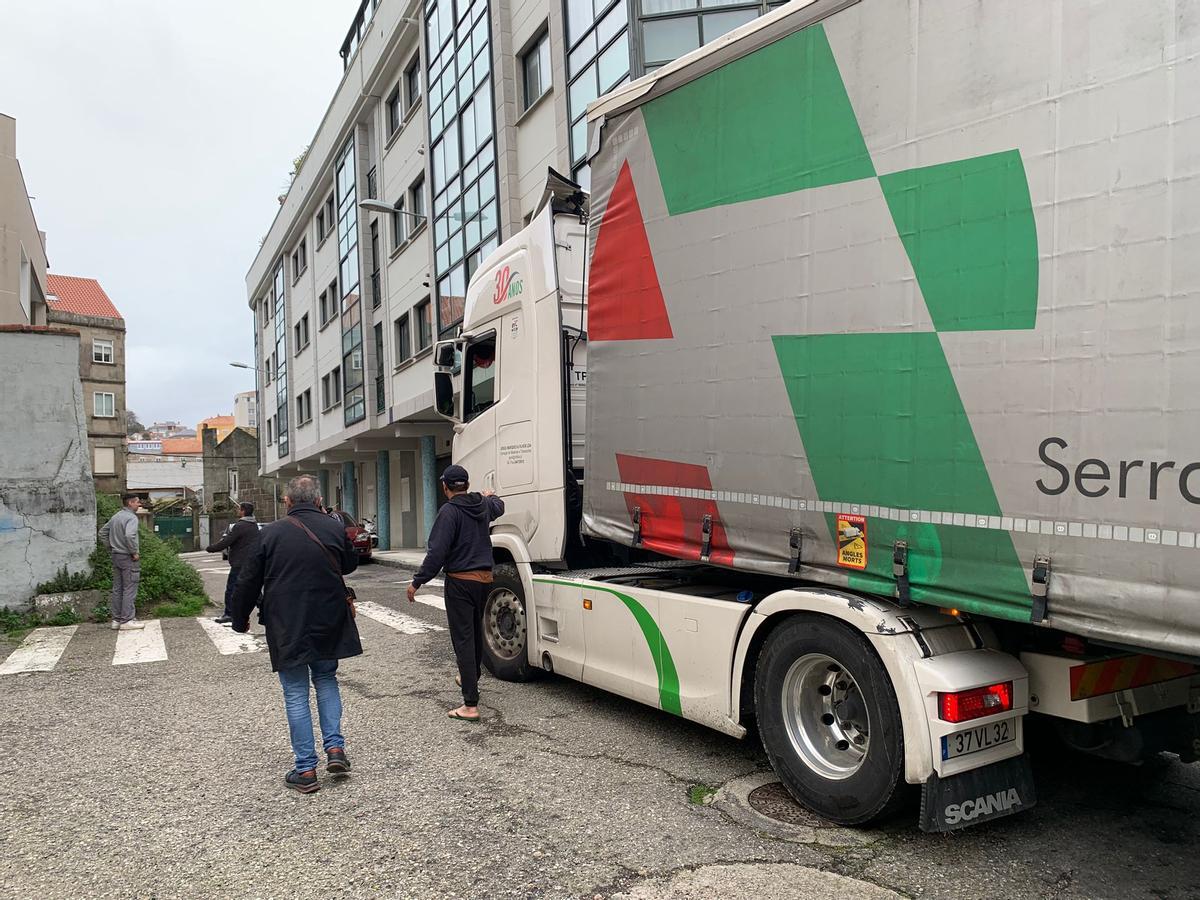 Vecinos intentan ayudar a desatascar al camión atrapado en una calle estrecha de Vigo.