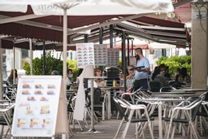 Un camarero atiende una mesa en la terraza de una cafetería 