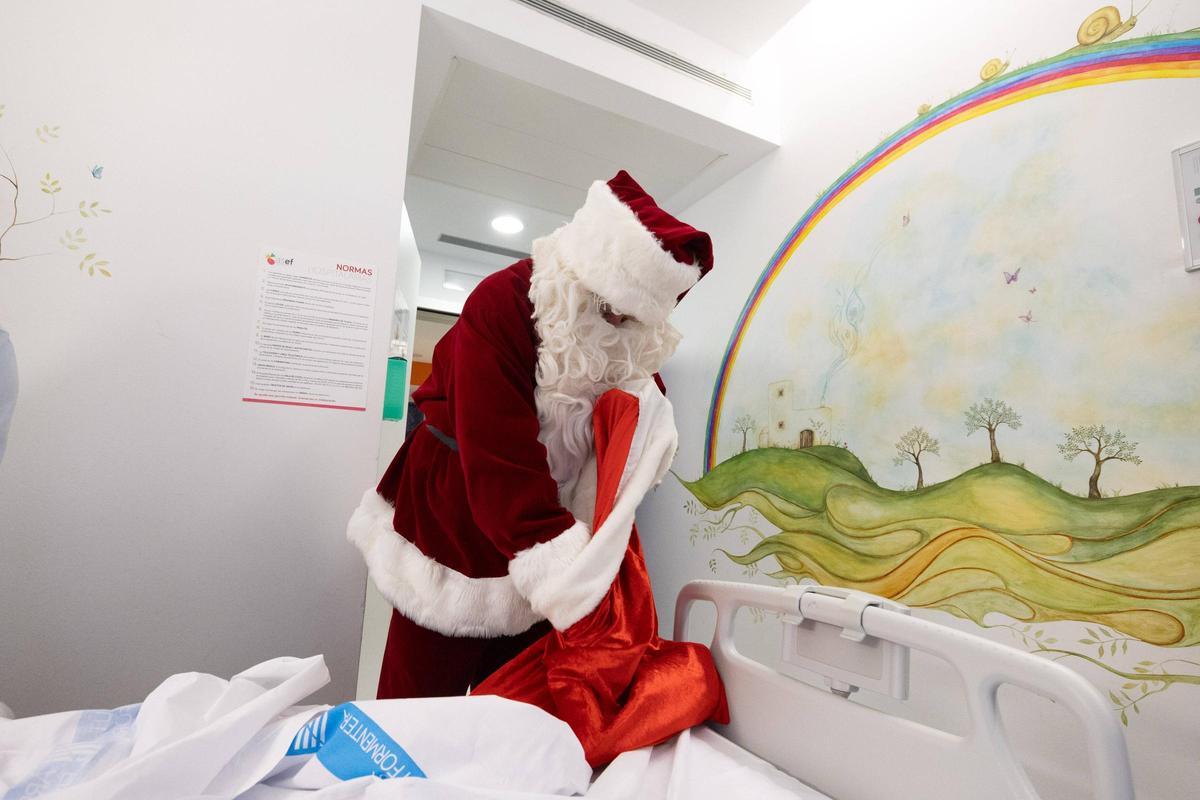 Papá Noel, busca unos regalos dentro de su bolsa.