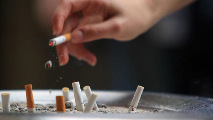 Un fumador apaga su cigarro en un cenicero.