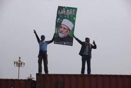 Supporters of Sufi cleric and leader of the Minhaj-ul-Quran religious organisation Muhammad Tahirul Qadri hold his poster over a container during a protest in Islamabad
