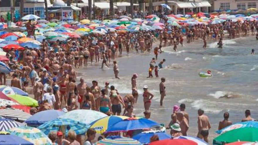 Una espectacular imagen en la que se observa cómo la playa del Cura está tomada por sombrillas y no se ve ni la orilla.