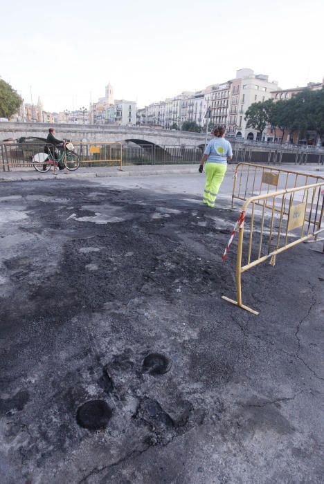 Carrers amb restes de mobiliari urbà cremat, contenidors per terra i treballadors de la brigada treballant