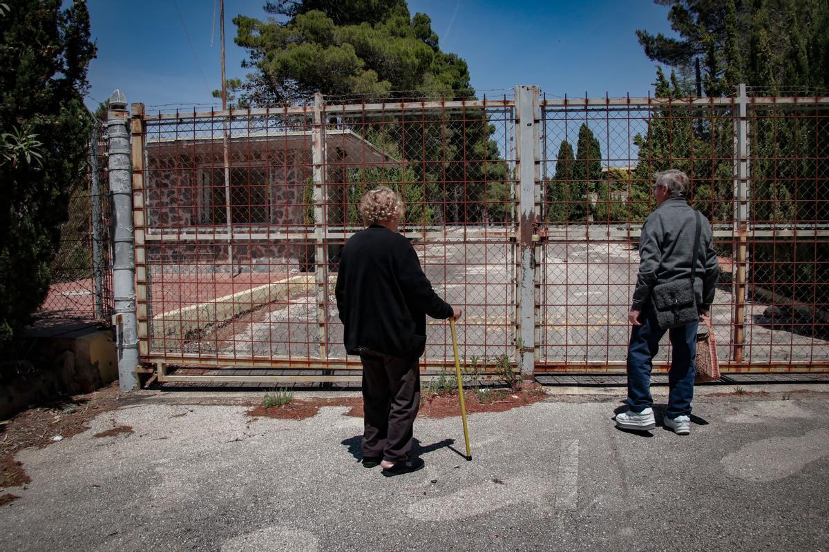 Dos personas observan el antiguo recinto militar desde la valla que impide el acceso, junto a la carretera que va de Alcoleja a Sella.