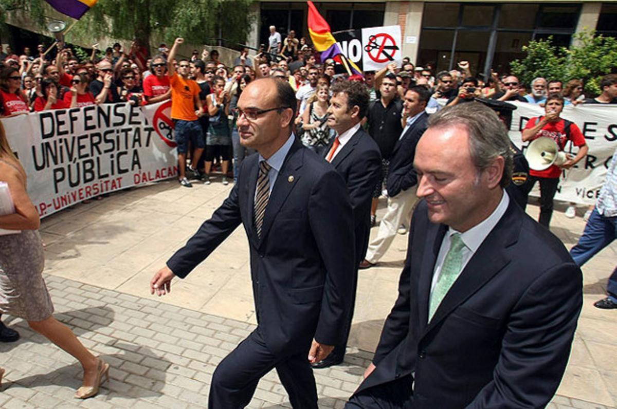El president de la Generalitat Valenciana, Alberto Fabra (dreta), i el rector electe de la Universitat d’Alacant, Manuel Palomar, passen davant una protesta de professors, alumnes i personal universitari, a Sant Vicent del Raspeig.