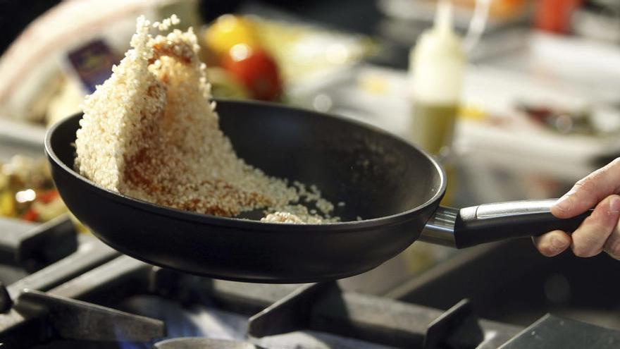 Un cocinero sostiene una sartén con cuscús.