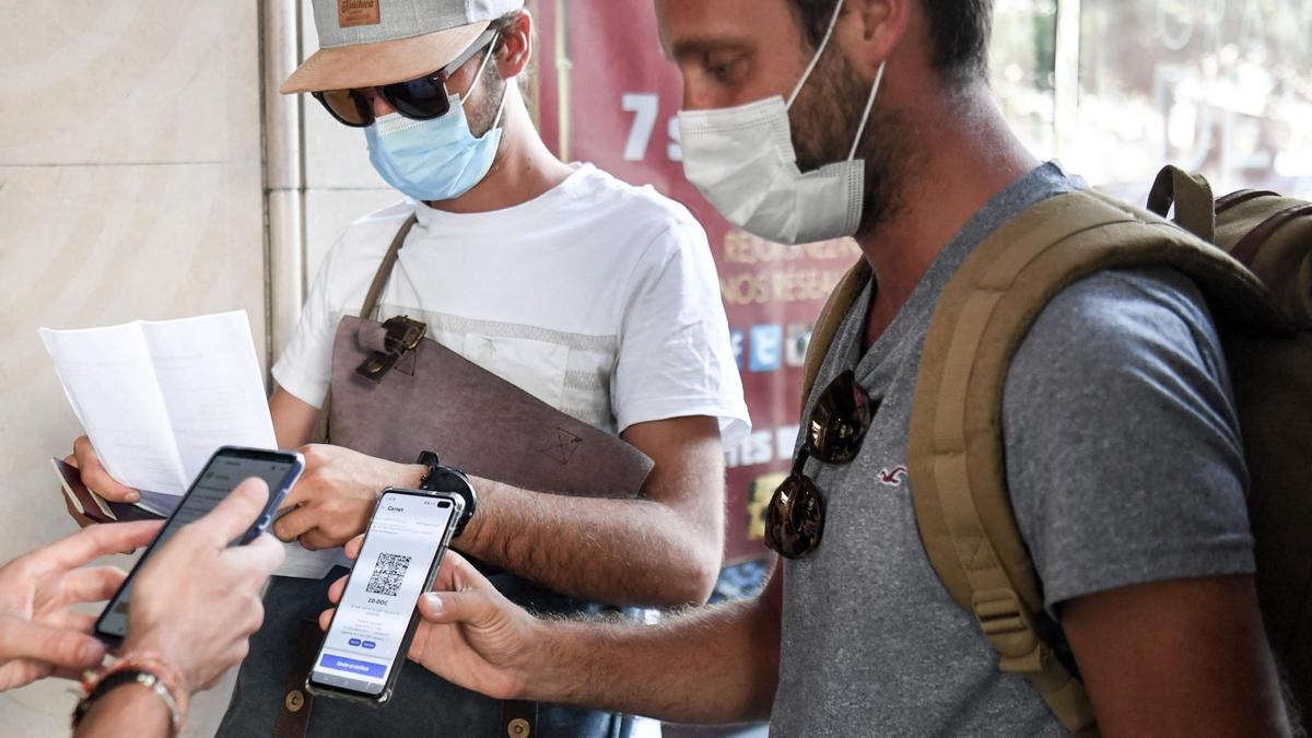 Unos espectadores enseñan su pasaporte sanitario antes de entrar al cine en París.