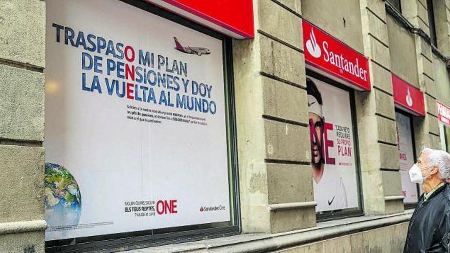 Un home llegeix cartells publicitaris de plans de pensions d’una entitat financera a Barcelona | JORDI OTIX