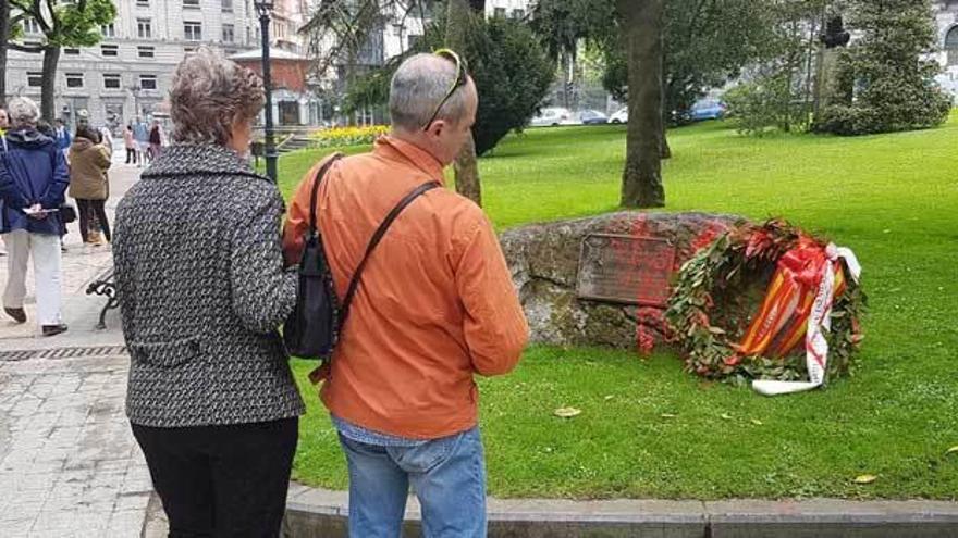 Dos paseantes, observando ayer el monolito, manchado con pintura roja.