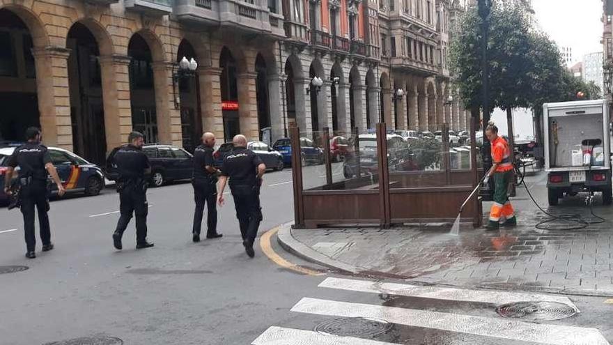 Agentes de la Policía Nacional se retiran del lugar de los hechos mientras una trabajadora de Emulsa limpia los restos de sangre de Marqués de San Esteban esquina con la calle Almacenes.